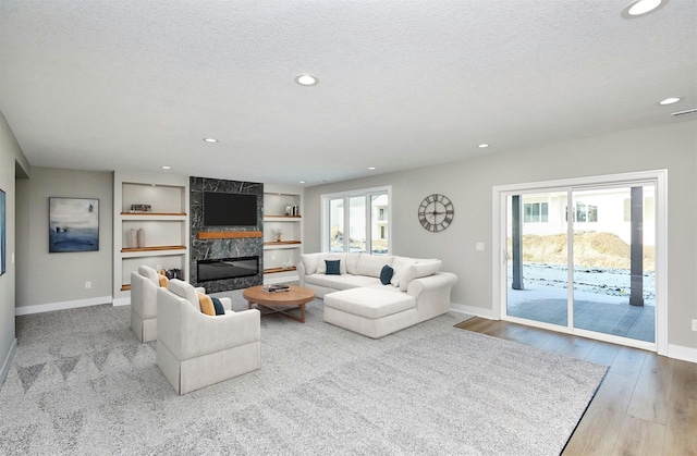 living room featuring a high end fireplace, a textured ceiling, and baseboards