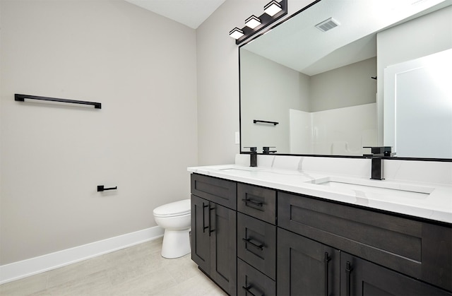 bathroom featuring toilet, a sink, visible vents, baseboards, and double vanity