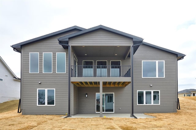 rear view of property with a yard, a patio area, and a balcony