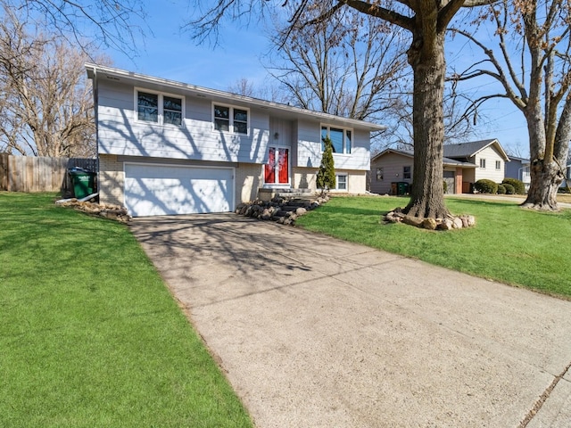 split foyer home with driveway, brick siding, an attached garage, fence, and a front yard