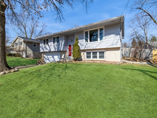 split foyer home featuring a front yard, brick siding, and an attached garage