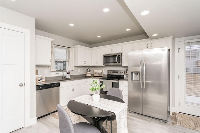 kitchen featuring appliances with stainless steel finishes, light wood-style floors, white cabinetry, a sink, and recessed lighting