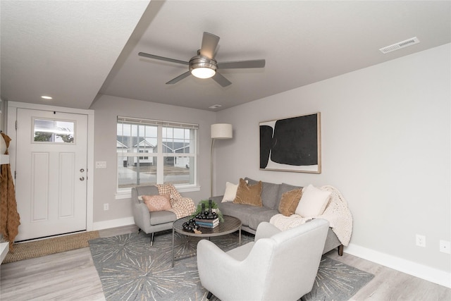 living room featuring ceiling fan, wood finished floors, visible vents, and baseboards