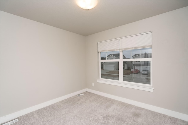 carpeted empty room featuring baseboards and visible vents