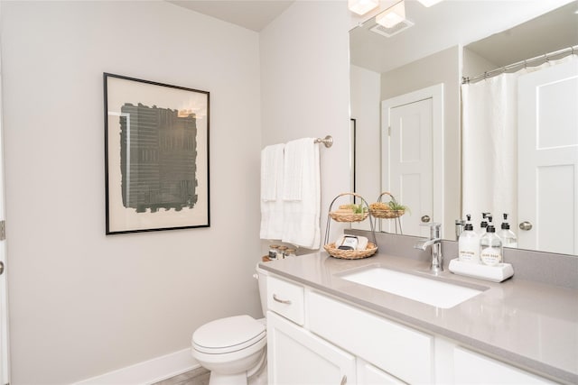 bathroom featuring toilet, baseboards, visible vents, and vanity