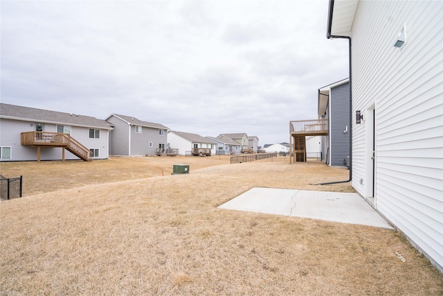 view of yard with a deck, stairway, fence, and a residential view