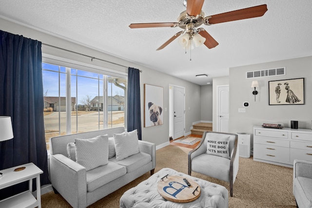 living area featuring visible vents, baseboards, light colored carpet, stairs, and a textured ceiling