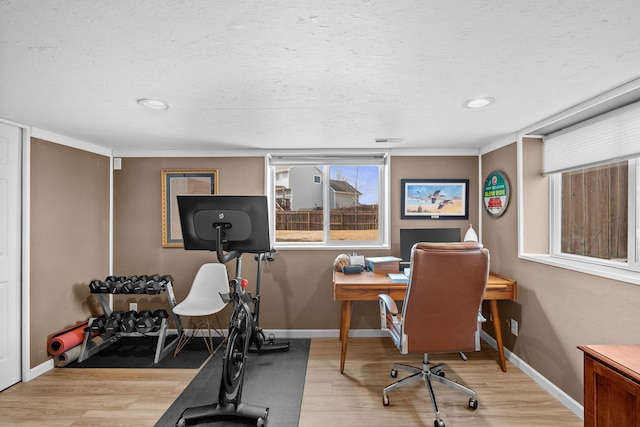 home office featuring baseboards, light wood-type flooring, and a textured ceiling