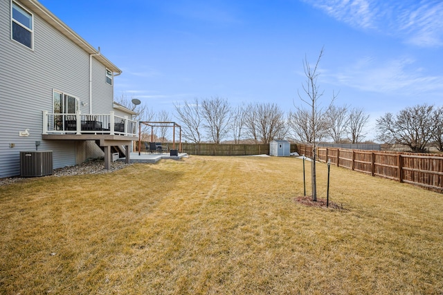 view of yard featuring a storage unit, a deck, central AC, a fenced backyard, and an outdoor structure