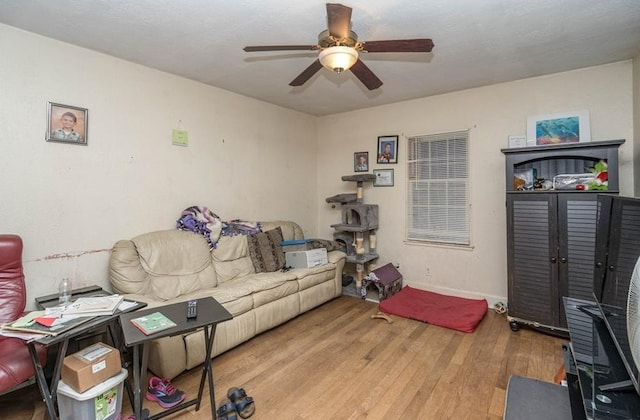 living room with ceiling fan, baseboards, and wood finished floors