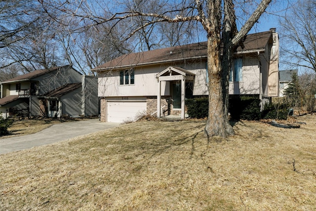 bi-level home featuring a garage, a front yard, brick siding, and driveway