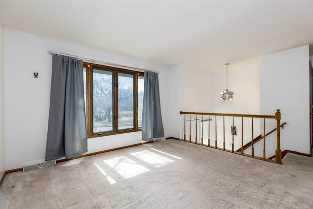 unfurnished room with a chandelier, visible vents, carpet floors, and baseboards