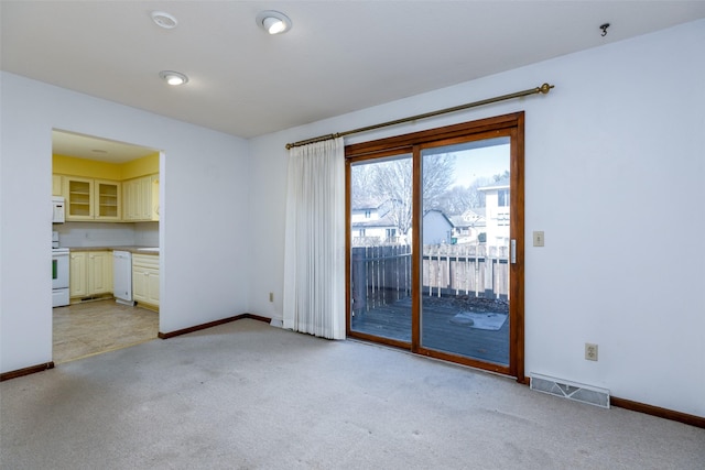 spare room featuring baseboards, visible vents, and light colored carpet