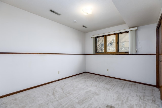 spare room with carpet floors, visible vents, and baseboards