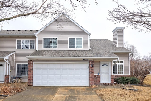 view of front of home with concrete driveway, brick siding, a chimney, and roof with shingles