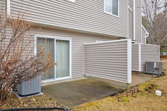 view of exterior entry featuring a patio and central AC unit