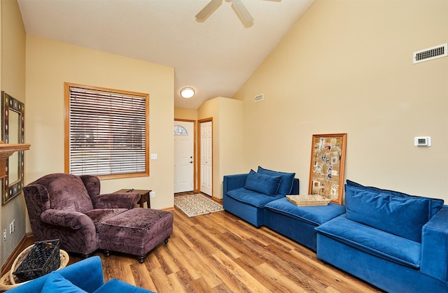 living area with a ceiling fan, visible vents, high vaulted ceiling, and wood finished floors