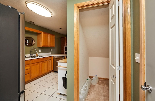 kitchen featuring light tile patterned floors, baseboards, appliances with stainless steel finishes, light countertops, and a sink