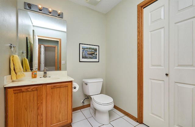 bathroom with tile patterned flooring, baseboards, vanity, and toilet