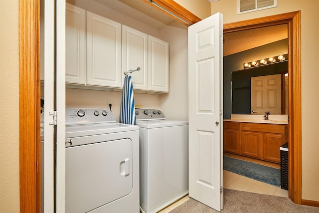 clothes washing area featuring cabinet space, light tile patterned floors, visible vents, washing machine and clothes dryer, and a sink