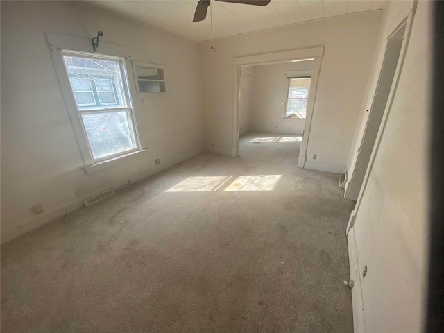 carpeted empty room with visible vents and a ceiling fan