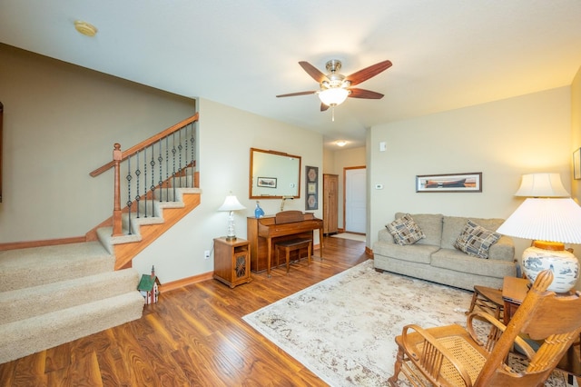 living area with ceiling fan, stairs, baseboards, and wood finished floors