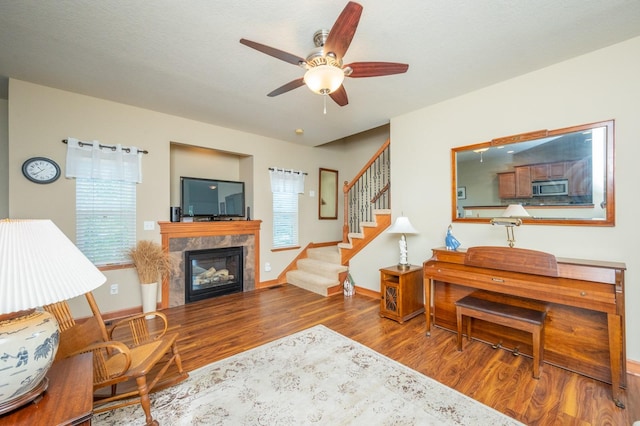 living room featuring stairs, baseboards, a fireplace, and wood finished floors