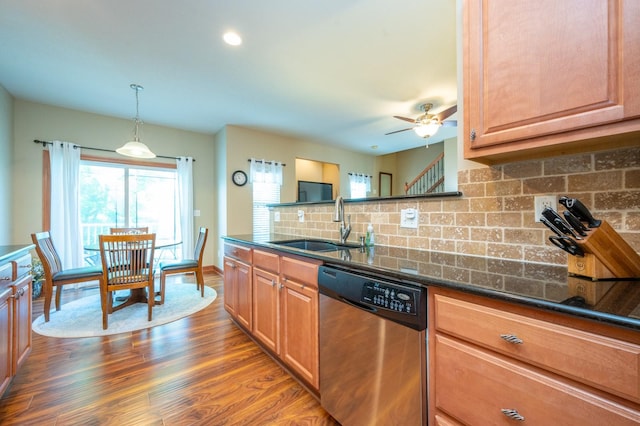 kitchen with dark stone counters, dishwasher, backsplash, wood finished floors, and a sink