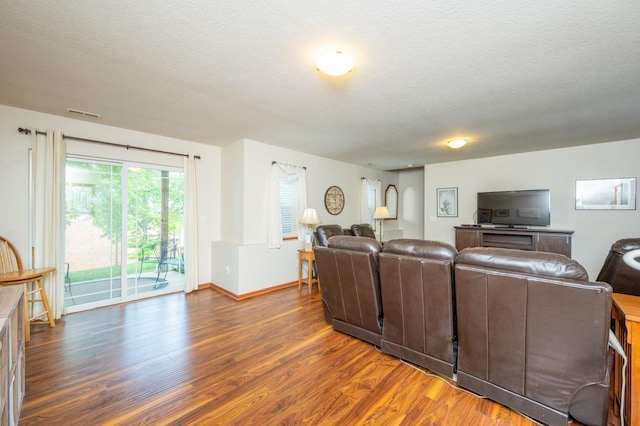 living area featuring dark wood-style floors, visible vents, baseboards, and a textured ceiling