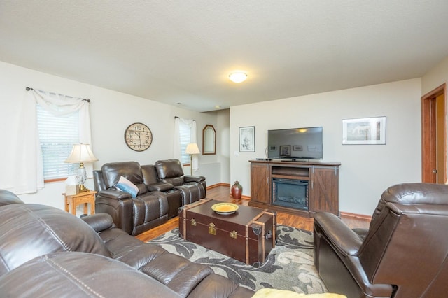 living area featuring a fireplace, baseboards, and wood finished floors