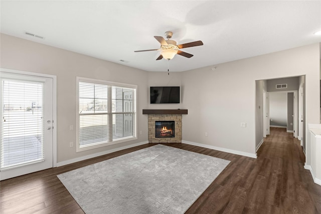 unfurnished living room with baseboards, a fireplace, visible vents, and dark wood-style flooring