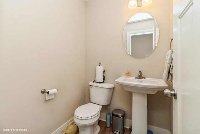 half bath with a sink, toilet, and baseboards