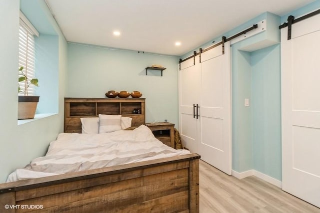 bedroom featuring baseboards, a barn door, light wood-style flooring, and recessed lighting