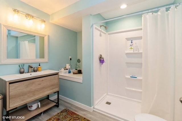 bathroom with toilet, vanity, wood finished floors, a shower with curtain, and baseboards