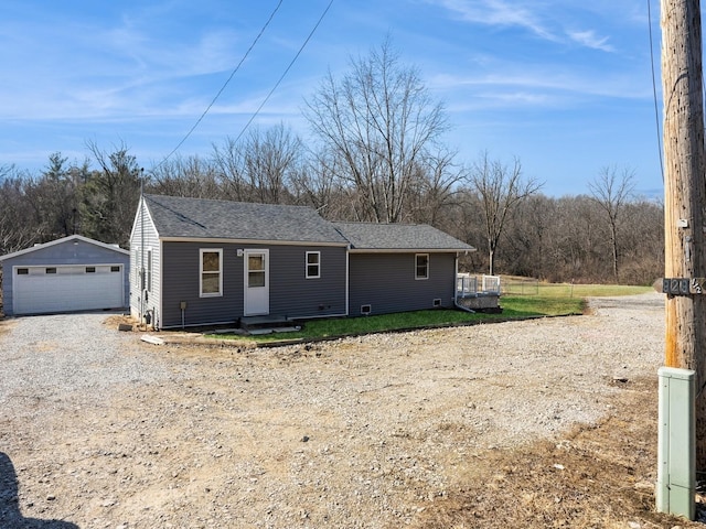 view of front of property featuring an outbuilding, roof with shingles, and a garage