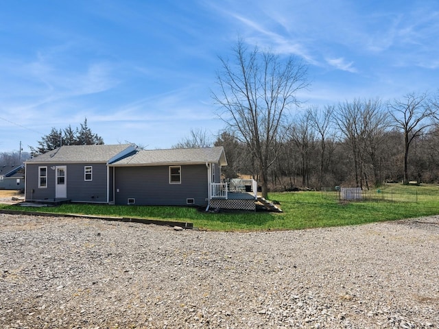 view of side of property with a deck, a yard, and fence