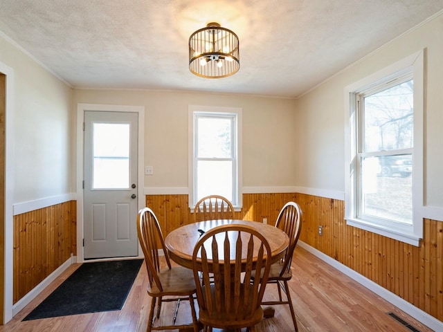 dining room featuring a wainscoted wall, visible vents, and wood walls