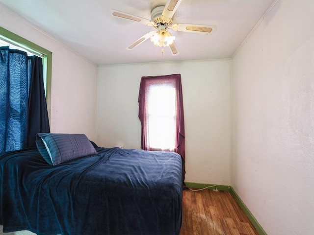 bedroom with baseboards, crown molding, a ceiling fan, and wood finished floors