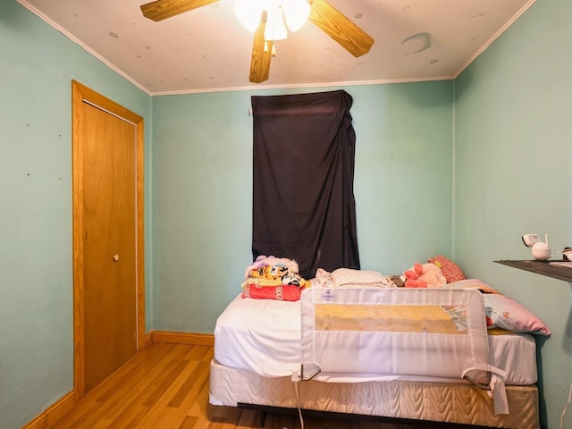 bedroom with crown molding, baseboards, ceiling fan, and wood finished floors