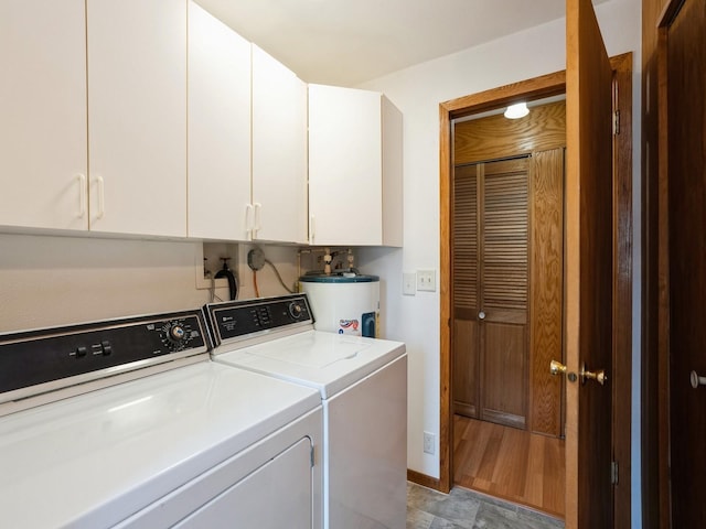 washroom with washer and dryer, water heater, cabinet space, and baseboards