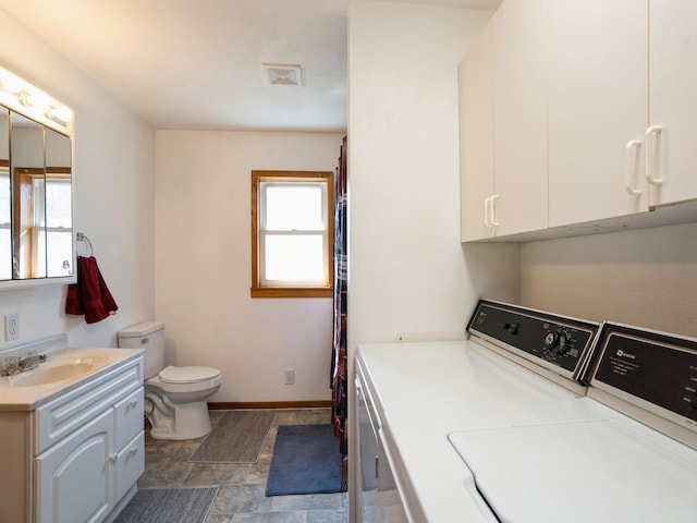 clothes washing area featuring visible vents, a sink, washer and dryer, laundry area, and baseboards