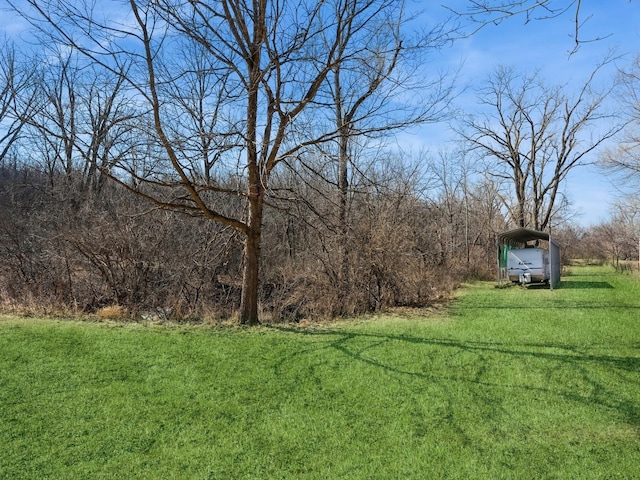 view of yard featuring a detached carport and a forest view