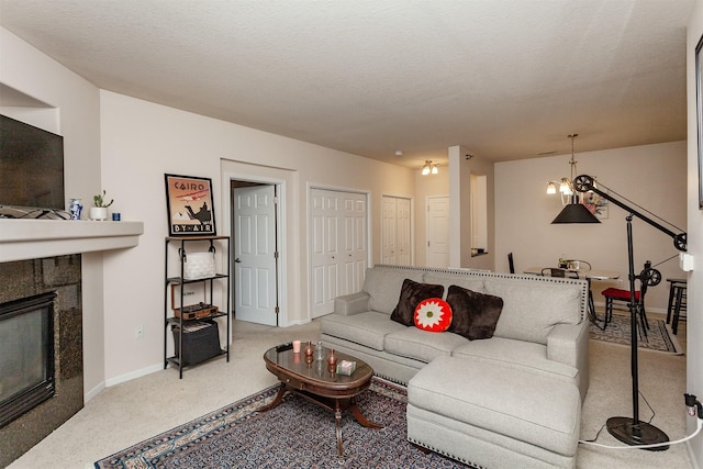 living room featuring carpet floors, a fireplace, a textured ceiling, and baseboards