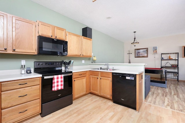 kitchen featuring a peninsula, light countertops, black appliances, light brown cabinets, and a sink