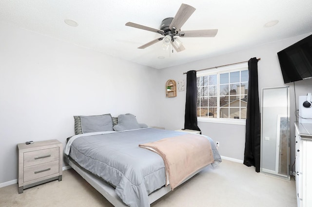 bedroom with light carpet, baseboards, and a ceiling fan