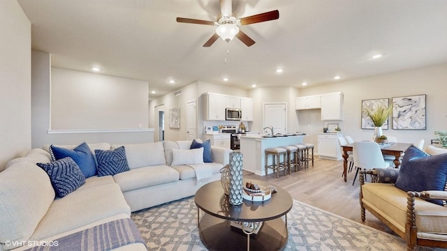 living room with recessed lighting, visible vents, ceiling fan, and light wood-style floors