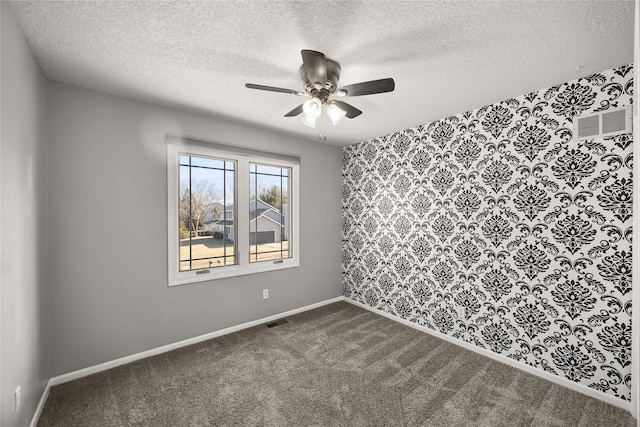 unfurnished room with a ceiling fan, visible vents, dark carpet, and baseboards