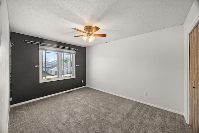 empty room with carpet, visible vents, ceiling fan, and baseboards