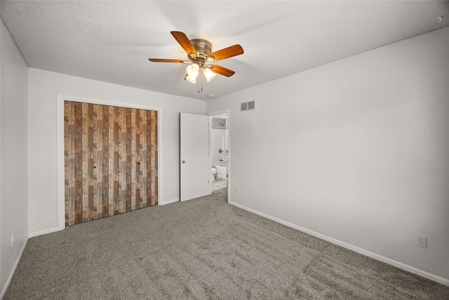 carpeted spare room with ceiling fan, a textured ceiling, visible vents, and baseboards