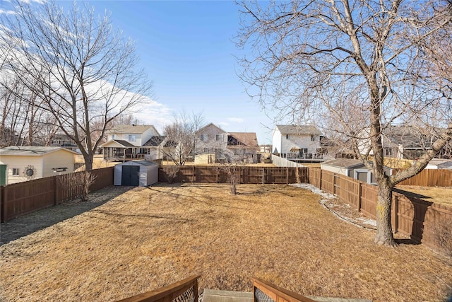 view of yard with a storage shed, an outbuilding, a fenced backyard, and a residential view